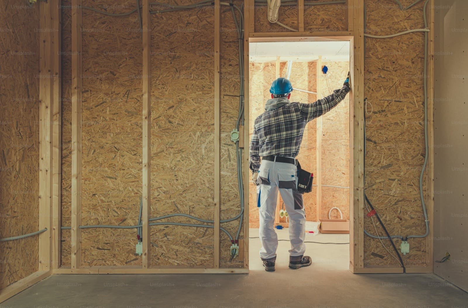 Electrician roughing-in wiring during new home construction